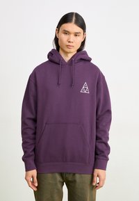 Sweat à capuche violet en mélange de coton, avec une poche avant, un cordon de serrage à la capuche et un logo triangulaire blanc sur la poitrine. Design décontracté.