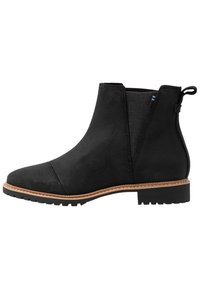 Botte de cheville en suede noir avec des panneaux élastiques sur les côtés, bout rond et semelle en caoutchouc texturé. Présente une languette à l'arrière et des coutures contrastées discrètes.