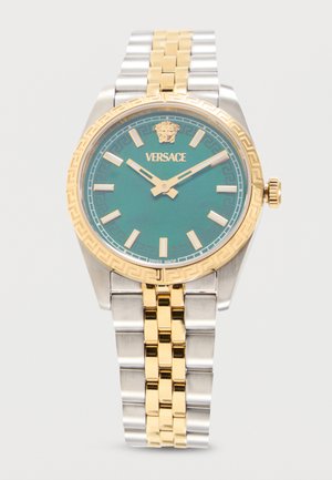 Πολυτελές ρολόι Versace με πράσινο καντράν, χρυσούς δείκτες και δείκτες ώρας, χρυσή στεφάνη με μοτίβο ελληνικού κλειδιού και δίχρωμο ασημένιο και χρυσό μεταλλικό μπρασελέ.
