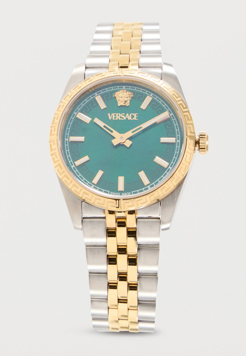 Πολυτελές ρολόι Versace με πράσινο καντράν, χρυσούς δείκτες και δείκτες ώρας, χρυσή στεφάνη με μοτίβο ελληνικού κλειδιού και δίχρωμο ασημένιο και χρυσό μεταλλικό μπρασελέ.