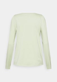 Maglietta verde chiaro a maniche lunghe con scollo rotondo. Realizzata in materiale morbido, presenta dettagli arricciati delicati sulle cuciture delle spalle.
