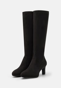 Bottes noires montantes en daim doux, avec une finition lisse, un bout rond et un talon moyen pour une élévation. Pas de quincaillerie visible.