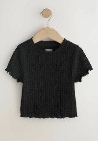 Zwart gestructureerd kortermig topje met een ronde halslijn, voorzien van een gekreukte stof en een gegolfde zoom, weergegeven op een houten kledinghanger.