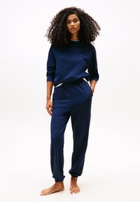 Marineblauwe sweatshirt en broekset gemaakt van zachte stof; heeft ribgebreide manchetten, een ontspannen fit en een klein logo op de borst.