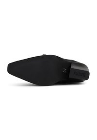Semelle de chaussure noire avec une finition lisse, un talon légèrement surélevé et un motif de grip texturé. Présente le nom de la marque gravé sur le côté.