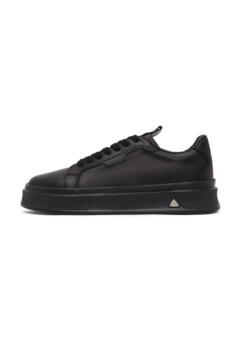 Sneaker in pelle nera con punta arrotondata, suola testurizzata e lacci frontali. Presenta un accento metallico triangolare su un lato.