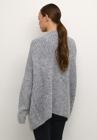Grijze oversized gebreide trui met een gestructureerde afwerking, featuring een high-low zoom en verlaagde schouders. Zachte en losse pasvorm.