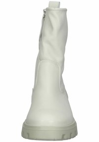 Botas de tobillo de cuero blanco con una textura suave, caña con cremallera lateral y una suela de goma gruesa para tracción.