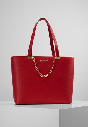 Rode faux leren shopper met een gladde textuur, gouden kettingaccent en dubbele draagriemen. Heeft een logo in het midden. Vierkante vorm.