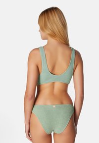 Mörkgrön ribbad bikiniuppsättning med topp med rundad rygg och matchande bottnar, som har en slät textur och en liten logodetalj på baksidan.