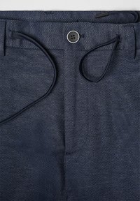 Marineblaue Hose mit strukturiertem Gewebe, ausgestattet mit einem Knopfverschluss und Kordelzug. Inklusive Gürtelschlaufen und glatter Oberfläche.