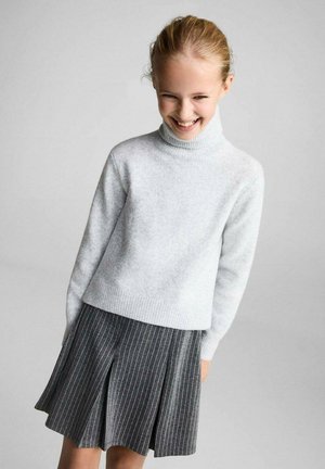Pull à col roulé gris clair en tissu doux, associé à une jupe plissée gris foncé avec des rayures verticales blanches.
