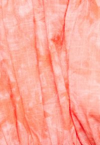 Tecido leve e texturizado numa suave tonalidade coral, com variações subtis e pregas, apresentando uma aparência natural e arejada.
