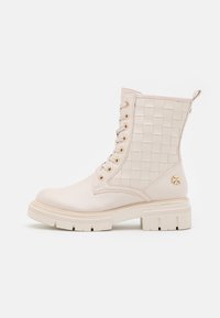 Botas blancas hasta el tobillo con una textura trenzada en los laterales, herrajes dorados y una suela gruesa para mayor durabilidad y estabilidad.