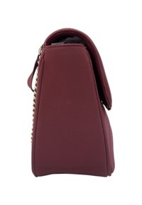 Vista laterale di una borsa bordeaux con chiusura a pattina e tracolla in catena argentata su uno sfondo bianco.