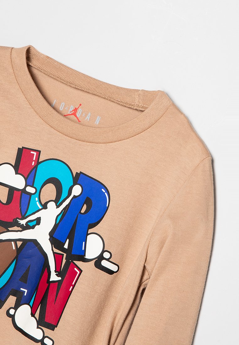 Camicia a maniche lunghe beige con il testo colorato "JORDAN" e il logo Jumpman bianco in posa da basket sul davanti.
