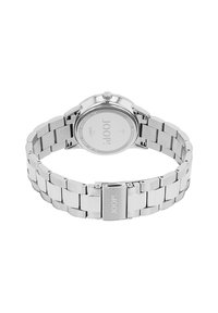 Srebrny zegarek ze stali nierdzewnej z okrągłą kopertą, siatkowym paskiem i zapięciem. Charakteryzuje się minimalistycznym designem i grawerowanym logo na pasku.