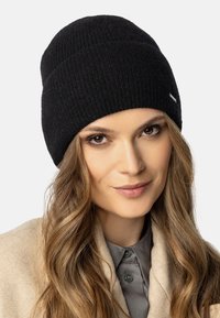 Gorro de punto negro hecho de material suave, con un patrón de acanalado horizontal y un pequeño acento de logo plateado en el lateral.