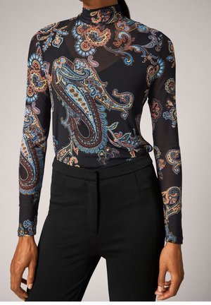 Haut noir près du corps à col roulé avec un motif cachemire coloré, associé à un pantalon noir sur mesure taille haute, montré du cou jusqu’aux hanches.