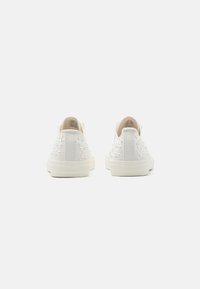 Sneaker bianchi in tela con accenti decorativi in perle sui lati, punta arrotondata e suola in gomma piatta. Vista posteriore con un design a profilo basso.