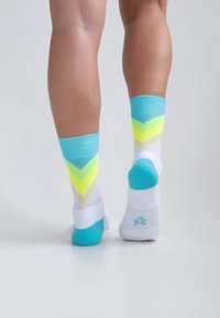 Colorful ankle socks in white, turquoise, and neon yellow. Features a chevron design with a smooth texture and contrasting heel and toe accents.