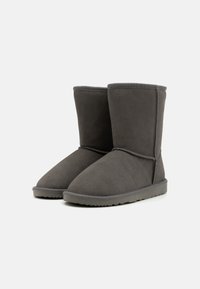 Grå mocka ankelboots med en slät yta, rund tå och en platt gummisula. Har sömdekor längs sömmarna.