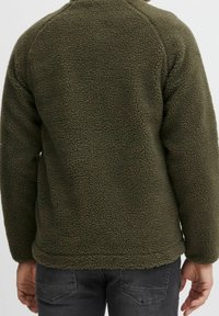 Oliwkowy polar z fakturowanej, pluszowej tkaniny, okrągłym dekoltem i rękawami raglanowymi, z długością do bioder.