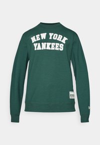 Grønn genser med "NEW YORK YANKEES" i hvit tekst over brystet, med et merke nederst til venstre og ribbestrikkede mansjetter.