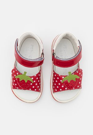 Sandales rouges pour tout-petits avec des pois blancs et des patchs verts en forme de fraises sur les brides, avec fermeture Velcro.