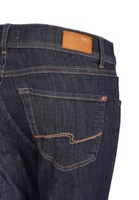 Dark blue denim jeans with five pockets, tan leather patch at the waistband, and orange stitching details. Standard fit and tapered design.
