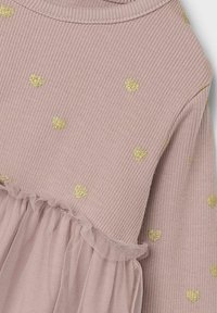 Abito rosa a coste con dettagli a forma di cuore dorati e una balza in tulle in vita. Texture morbida e scollatura rotonda.