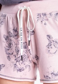 Rosa blommiga shorts i mjukt tyg med ribbat mönster, utrustade med ett vitt snöre med texten "LAVIE EN ROSE" och dekorativ sömnad.