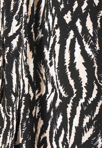 Tissu à imprimé zèbre noir et blanc avec des rangées verticales de boutons noirs sur un vêtement, gros plan.