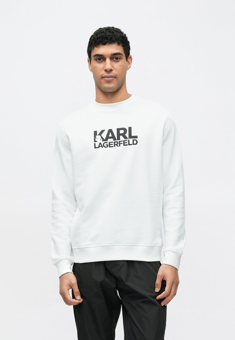 Bílá mikina s kulatým výstřihem, s výrazným černým logem "KARL LAGERFELD" na přední straně. Texturovaná tkanina, dlouhé rukávy.