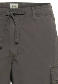 Graue Cargo-Shorts mit einem Kordelzugbund, Seitentaschen und einem leichten, strukturierten Stoff. Gestickte Details betonen das Design.
