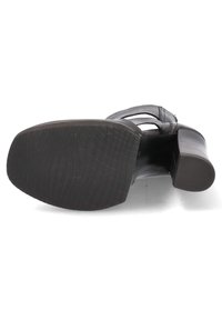 Black heeled sandal with cut-out design, smooth leather material, and textured rubber outsole. Features a tapered heel and adjustable strap.