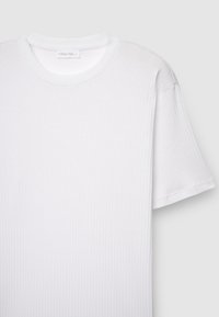 Weißes, geripptes Baumwoll-T-Shirt mit Rundhalsausschnitt, kurzen Ärmeln und einem Etikett mit der Aufschrift „Calliope Man L“ im inneren Halsbereich.