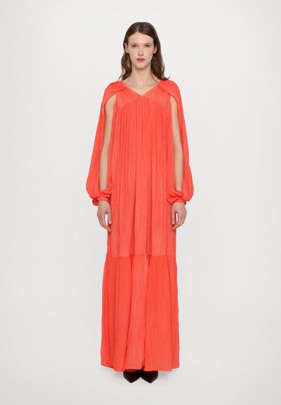 Maxi dress in bright coral with vertical pleating, open shoulders, and balloon sleeves; layered bottom for added volume and movement.