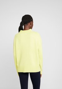 Lime zielony, oversized sweter dzianinowy z ribbowanym dołem i kołnierzem, charakteryzujący się luźnym krojem i długimi rękawami.