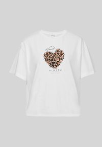 Balts īsās piedurknes T-krekls ar leopardu rakstu sirdī un melniem rakstainiem vārdiem "MANAS SIRDS ir savvaļas". 100% kokvilna.