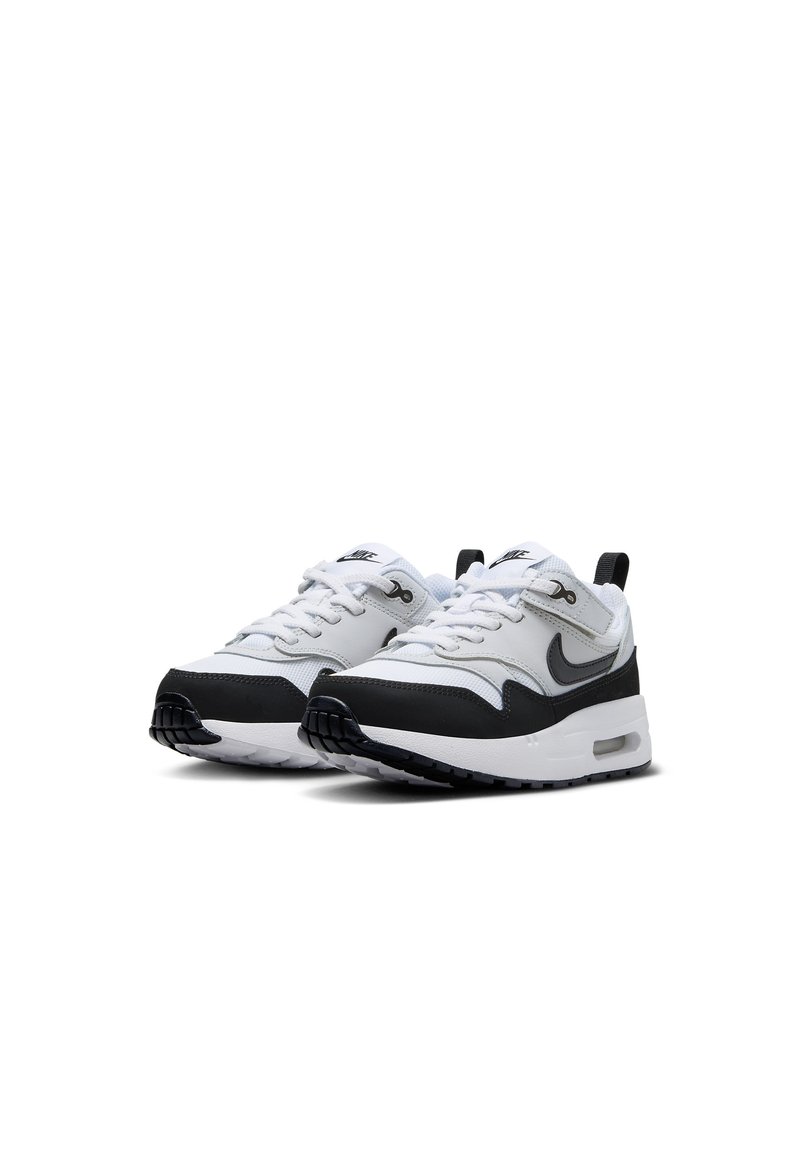 Witte en zwarte sport sneakers met een gestructureerde zool, vetersluiting, gewatteerde kraag en een prominent Nike-logo aan de zijkant.