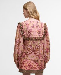 Bluza roz cu model floral are mâneci voluminoase, guler cu volane și accente verzi. Este realizată dintr-un material ușor și are desene complexe.