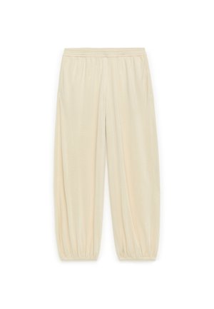 Šviesiai smėlinės spalvos, elastinga juostos kelnės su susiraukšlėmis prie rankovių. Minkšta medžiaga, siaurėjanti forma ir šoninės kišenės. Tinka laisvalaikio aprangai.