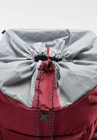Rode stoffen rugzak met een strakke grijze trekkoordsluiting, voorzien van zwarte accenten en een gestructureerd patroon aan de zijkant.