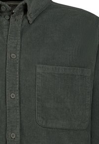 Dunkelgrünes Cordhemd mit Frontknöpfen, Brusttasche und einem strukturierten gerippten Stoffmuster.