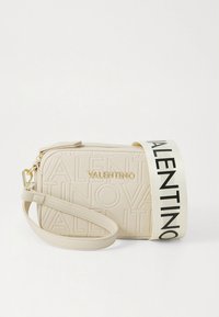 Beige lærveske med tversover stropp, preget logo, gullfarget beslag og en kontrastfylt svart stropp med navnet "VALENTINO".