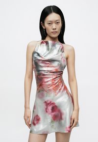 Mini haljina od satena s cvjetnim uzorcima u nijansama ružičaste i crvene, s naboranim izrezom i tankim naramenicama. Glatka, reflektirajuća tekstura.