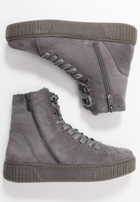 Bottes cheville en daim gris avec semelles texturées, équipées d'une fermeture éclair et d'un laçage. Les accents incluent des œillets en métal et une doublure moelleuse.