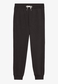 Schwarze Jogginghose aus einem weichen Stoff, mit einem elastischen Bund und weißem Kordelzug sowie seitlichen Taschen. Rippstrickbündchen an den Knöcheln.