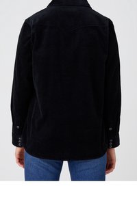 Black corduroy shirt with long sleeves, a pointed collar, and buttoned cuffs. Features vertical ribbing texture and curved hem.